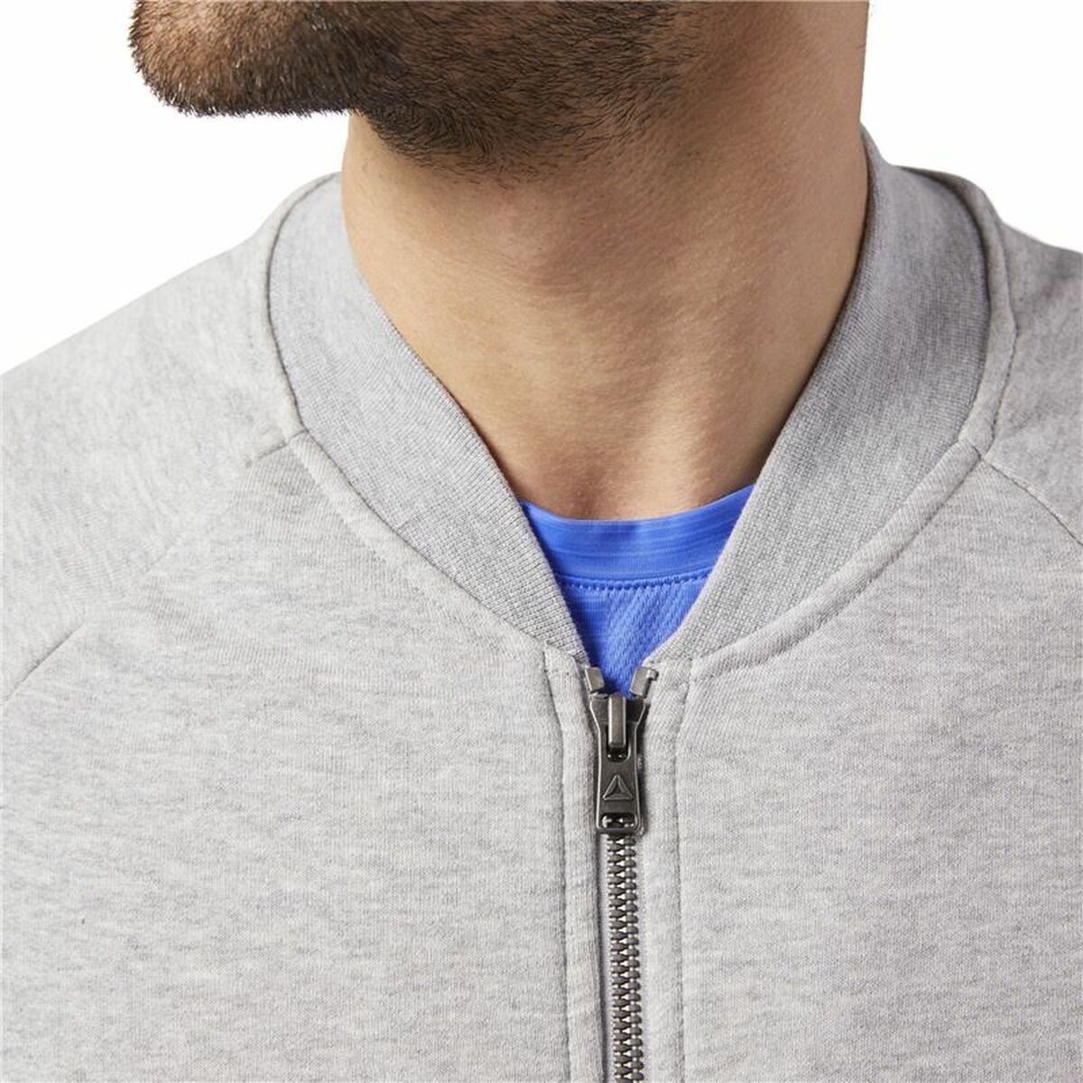 "Detaljbild av tyg och struktur på Reebok Bomber Retro tröja grå."