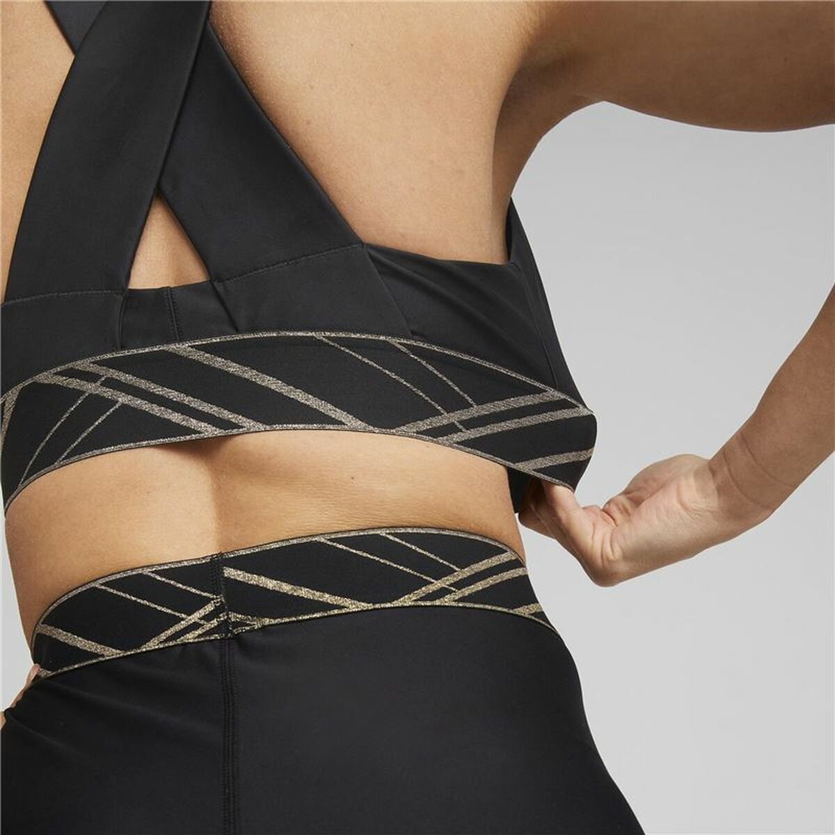 "Detaljbild på resårbandet och logotypen på Puma Mid Impact Deco Glam svart sport-bh."